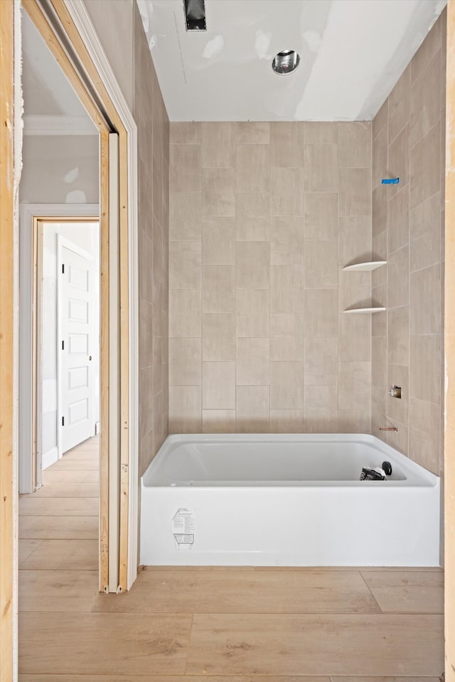 bathroom with tile walls, hardwood / wood-style floors, and a washtub