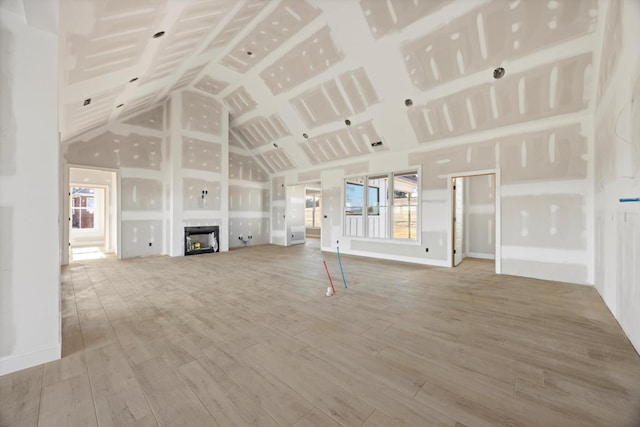 unfurnished living room featuring hardwood / wood-style flooring, high vaulted ceiling, and a fireplace