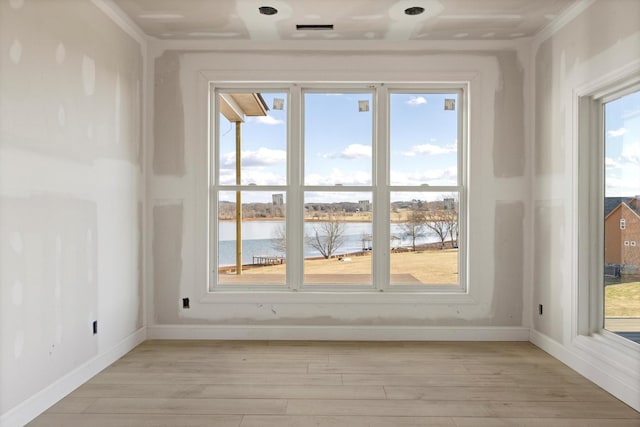 spare room featuring a water view and light hardwood / wood-style flooring