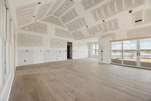 unfurnished living room featuring a water view and light hardwood / wood-style flooring