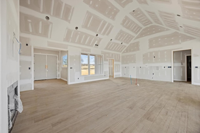 unfurnished living room with lofted ceiling and light wood-type flooring