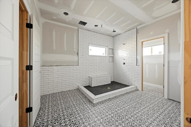 bathroom featuring walk in shower and brick wall