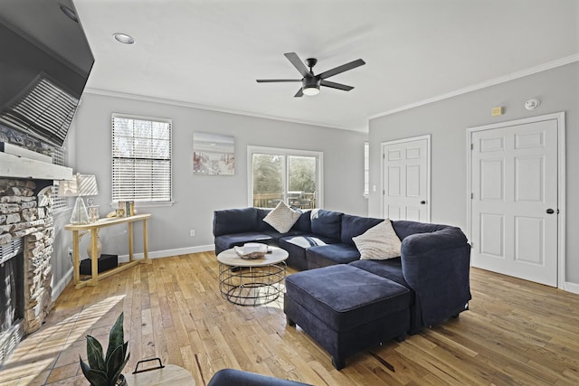 living room featuring crown molding, a stone fireplace, light hardwood / wood-style flooring, and ceiling fan