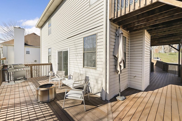 wooden deck with grilling area and an outdoor fire pit