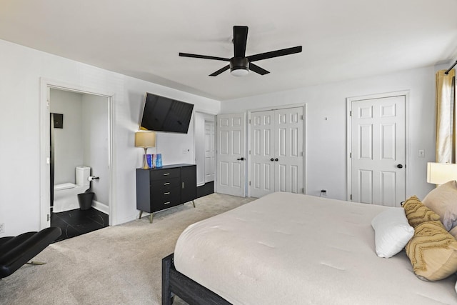 bedroom with connected bathroom, two closets, ceiling fan, and dark colored carpet