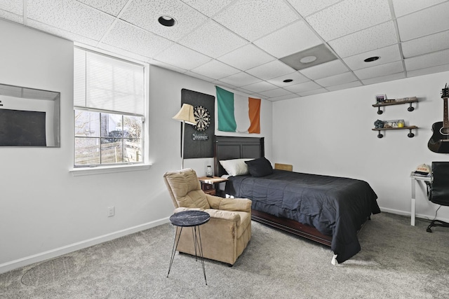 carpeted bedroom featuring a drop ceiling