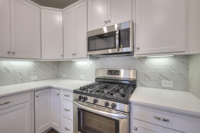 kitchen with decorative backsplash, white cabinets, and appliances with stainless steel finishes