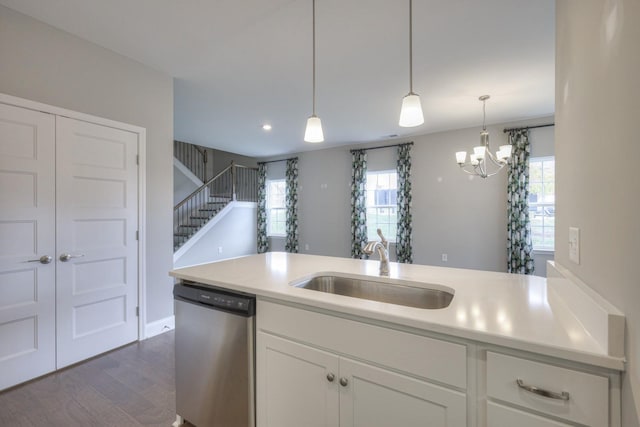 kitchen featuring dark wood-type flooring, sink, white cabinetry, decorative light fixtures, and stainless steel dishwasher