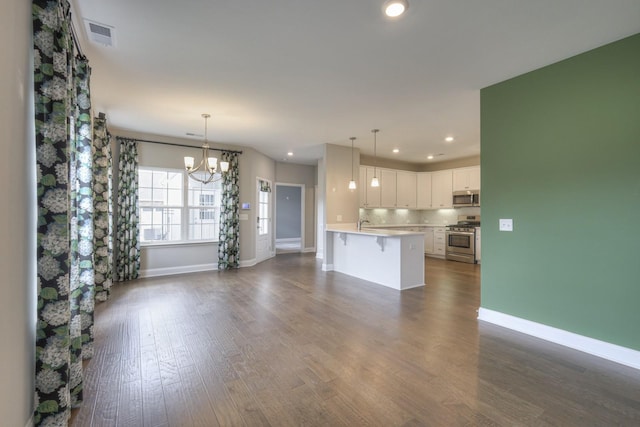 kitchen with white cabinetry, appliances with stainless steel finishes, a kitchen bar, and decorative light fixtures