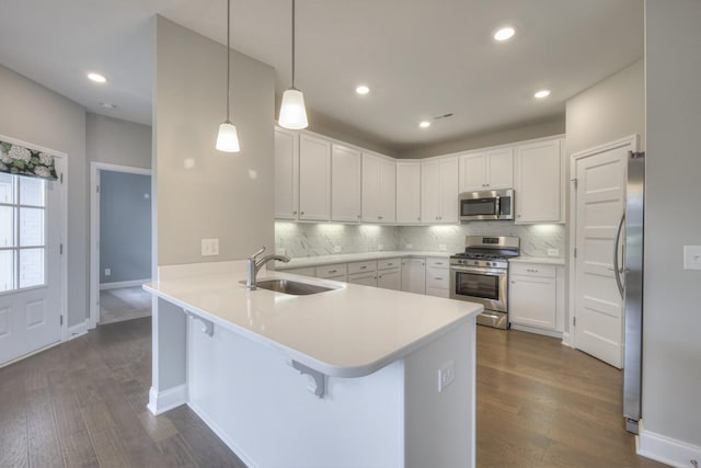 kitchen featuring sink, white cabinetry, hanging light fixtures, appliances with stainless steel finishes, and kitchen peninsula