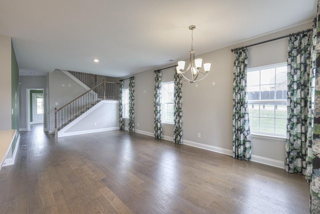 unfurnished living room with plenty of natural light, dark hardwood / wood-style floors, and a chandelier