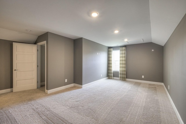 spare room with light carpet and vaulted ceiling