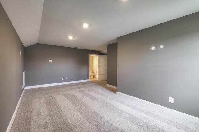 empty room featuring vaulted ceiling and light carpet