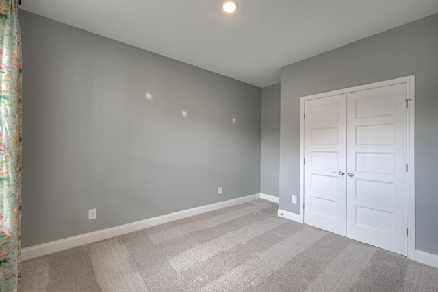 unfurnished bedroom with light carpet and a closet