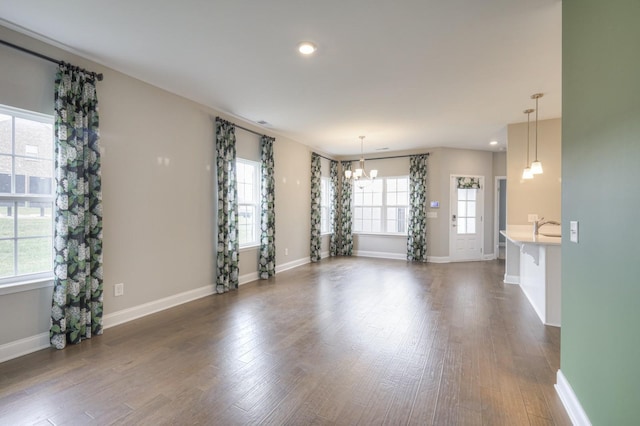 unfurnished room featuring sink, dark wood-type flooring, and a chandelier