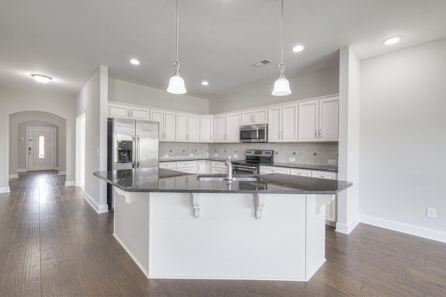 kitchen with backsplash, a kitchen breakfast bar, white cabinets, and appliances with stainless steel finishes