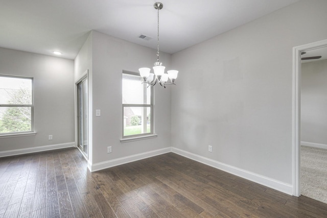 spare room with dark hardwood / wood-style floors and a notable chandelier