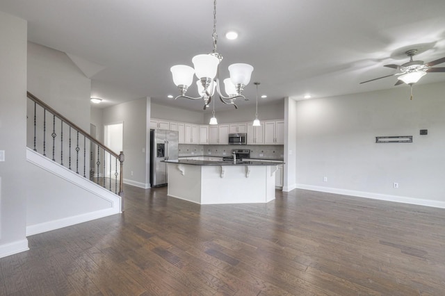 kitchen featuring appliances with stainless steel finishes, tasteful backsplash, an island with sink, white cabinets, and decorative light fixtures