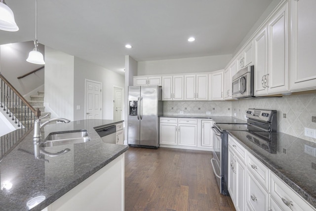 kitchen featuring decorative light fixtures, white cabinetry, sink, dark stone countertops, and stainless steel appliances