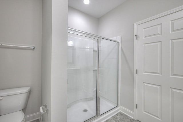 bathroom featuring toilet and a shower with door