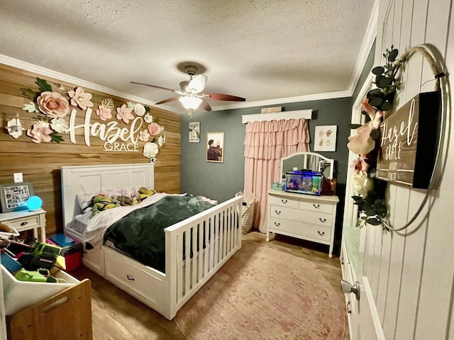 bedroom featuring crown molding, wooden walls, a textured ceiling, and ceiling fan