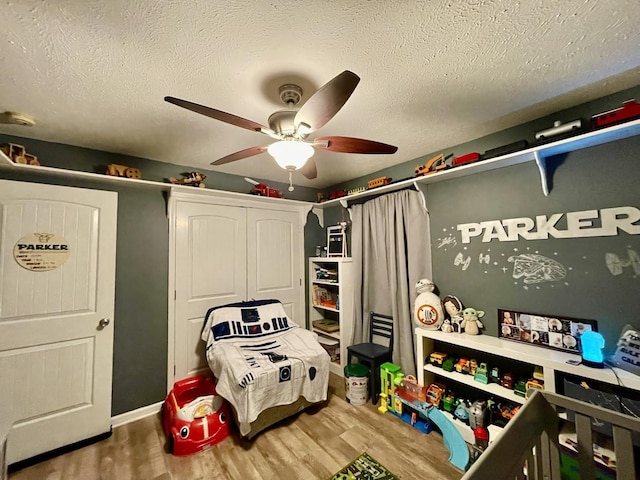 bedroom with a textured ceiling, wood-type flooring, and ceiling fan