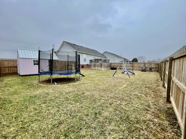 view of yard featuring a storage shed, a playground, and a trampoline