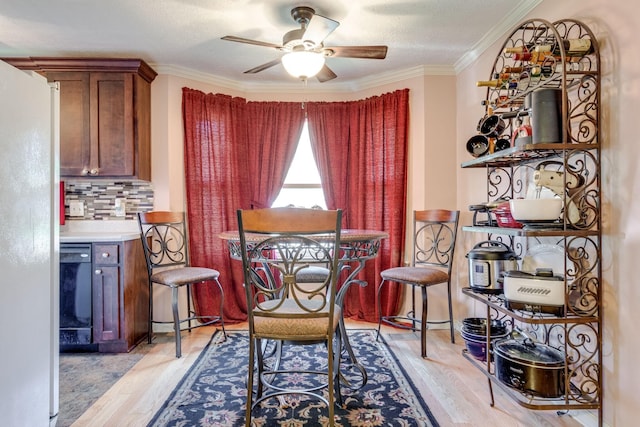 dining space with ceiling fan, light hardwood / wood-style flooring, ornamental molding, and a textured ceiling