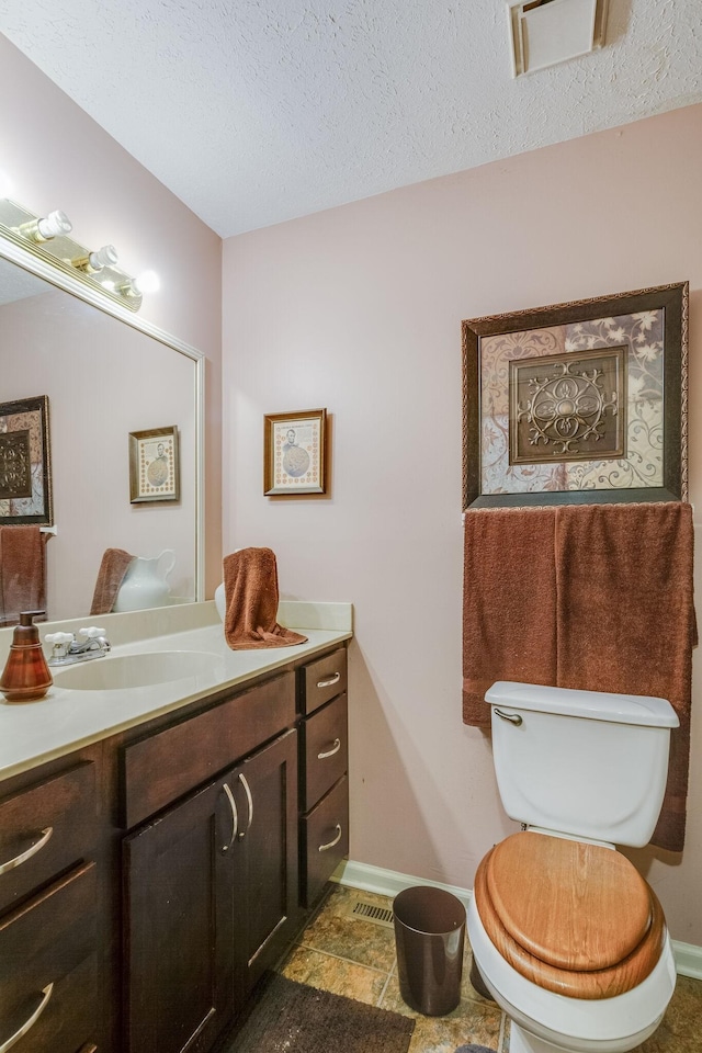 bathroom featuring vanity, toilet, and a textured ceiling