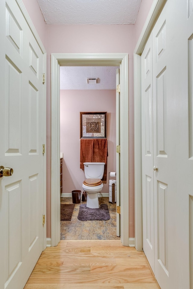 bathroom featuring hardwood / wood-style flooring, vanity, toilet, and a textured ceiling