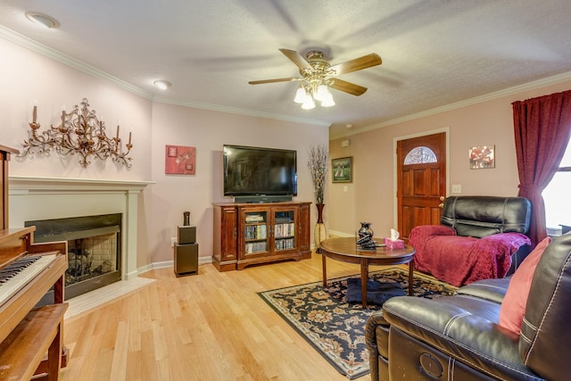 living room featuring crown molding, ceiling fan, a textured ceiling, and light wood-type flooring