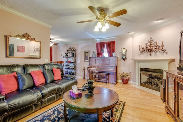 living room featuring ceiling fan, crown molding, light hardwood / wood-style floors, and a textured ceiling