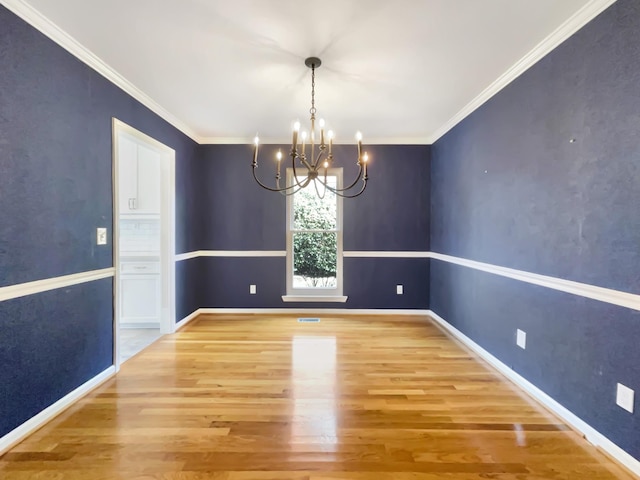 unfurnished dining area featuring ornamental molding, a chandelier, and light hardwood / wood-style floors