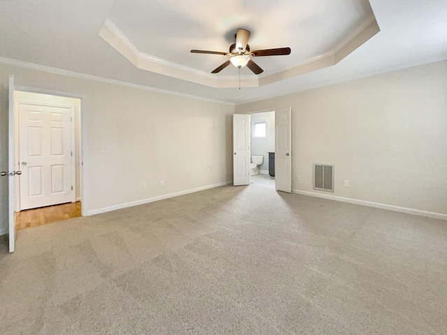 carpeted spare room with crown molding, a tray ceiling, and ceiling fan