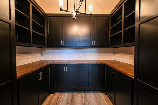 kitchen with butcher block counters, light hardwood / wood-style flooring, and an inviting chandelier