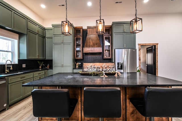 kitchen featuring stainless steel appliances, custom exhaust hood, sink, and a breakfast bar area