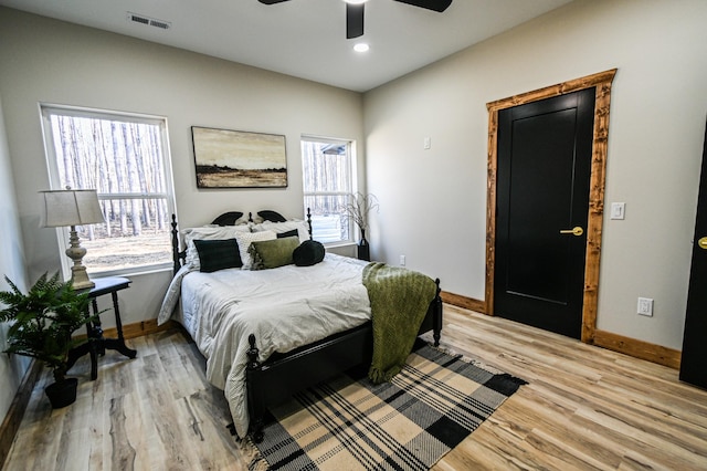 bedroom with multiple windows, light hardwood / wood-style floors, and ceiling fan