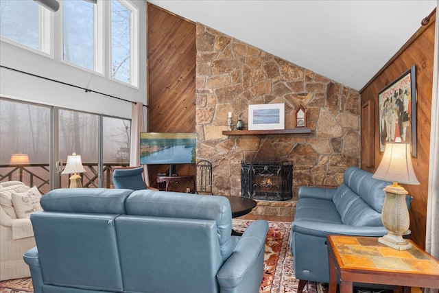 living room featuring a stone fireplace, plenty of natural light, and wood walls