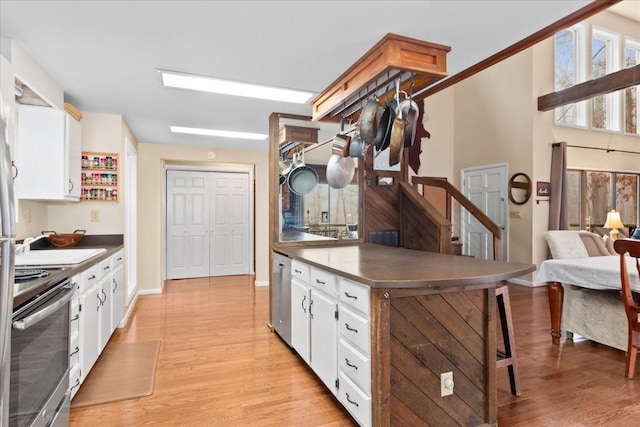 kitchen with stainless steel appliances, white cabinets, and light wood-type flooring