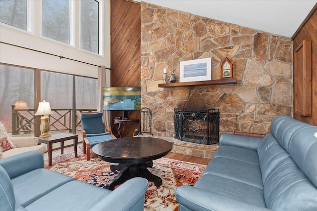 living room with hardwood / wood-style flooring, a stone fireplace, and high vaulted ceiling