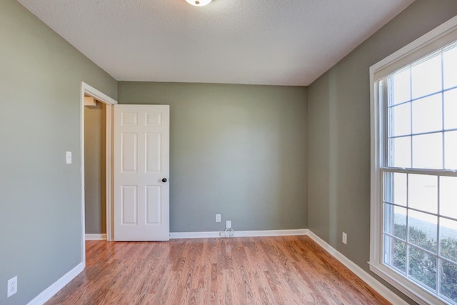 spare room with light hardwood / wood-style flooring and a textured ceiling