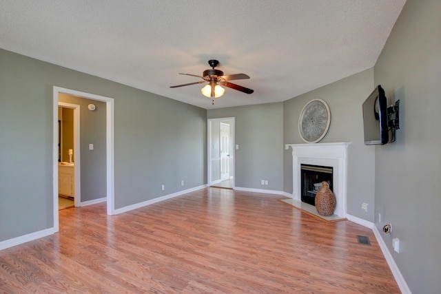 unfurnished living room featuring ceiling fan, a textured ceiling, and light wood-type flooring