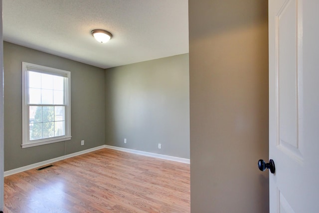 unfurnished room with light hardwood / wood-style flooring and a textured ceiling