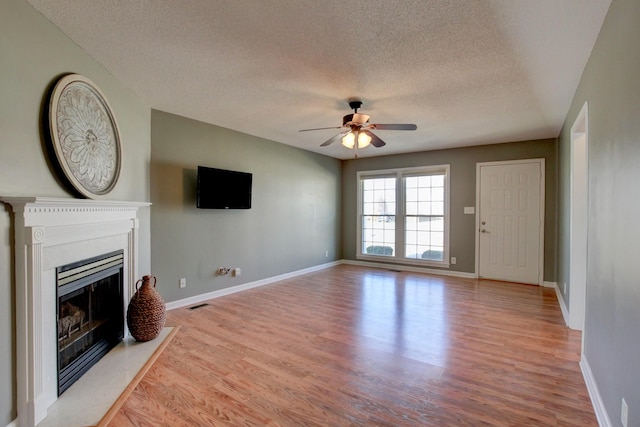 unfurnished living room featuring ceiling fan, a textured ceiling, and light hardwood / wood-style flooring