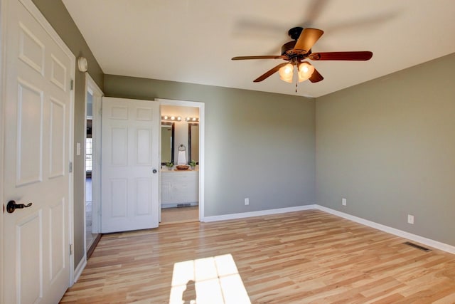 unfurnished bedroom with ensuite bathroom, light wood-type flooring, and ceiling fan