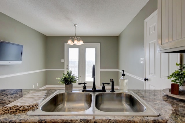 kitchen with hanging light fixtures, sink, a chandelier, and a textured ceiling