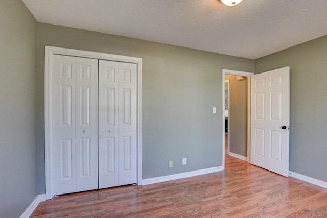 unfurnished bedroom featuring hardwood / wood-style flooring, a textured ceiling, and a closet