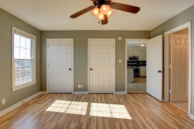 unfurnished bedroom with ceiling fan, light hardwood / wood-style floors, and two closets