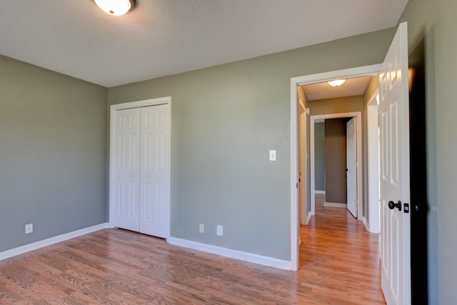 unfurnished bedroom with light hardwood / wood-style flooring, a closet, and a textured ceiling