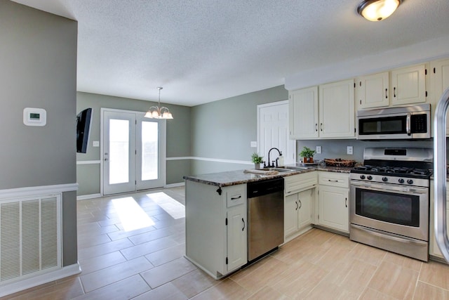 kitchen with sink, an inviting chandelier, kitchen peninsula, stainless steel appliances, and white cabinets